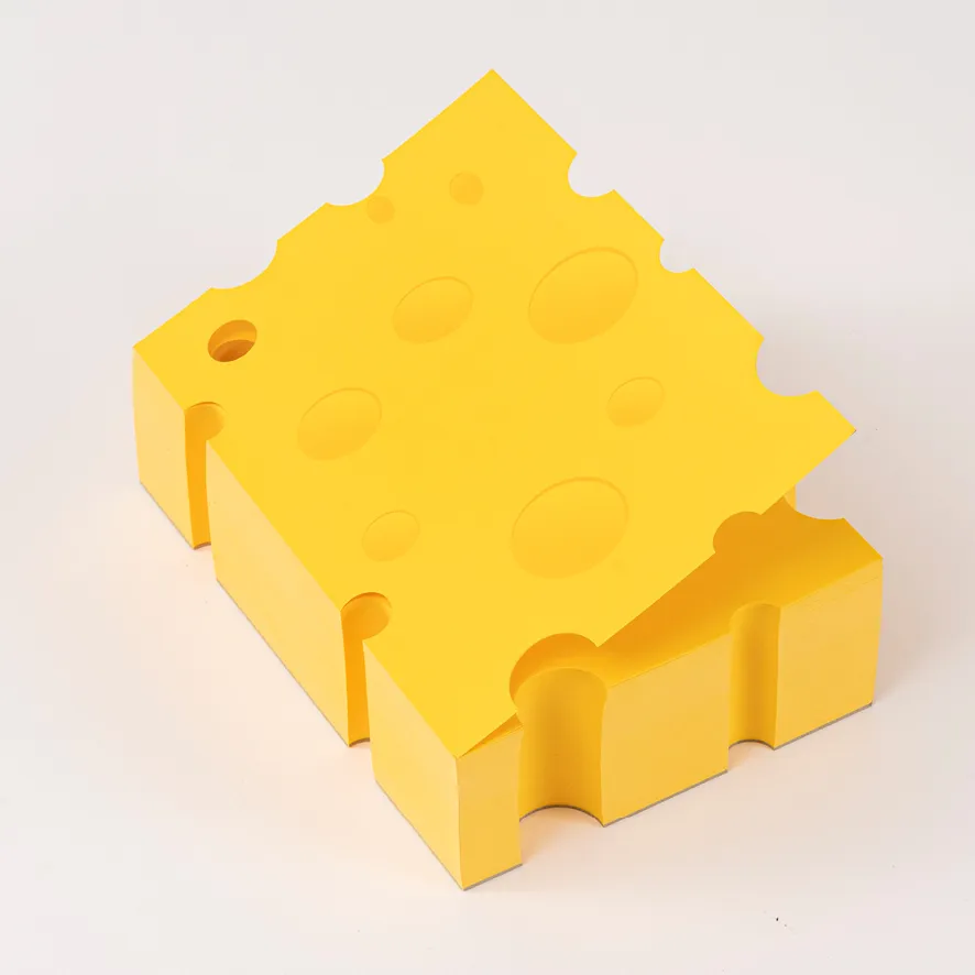 Ein gelber Zettelblock in Käseform mit runden Löchern, die durch den ganzen Stapel und an den Kanten entlang gehen.