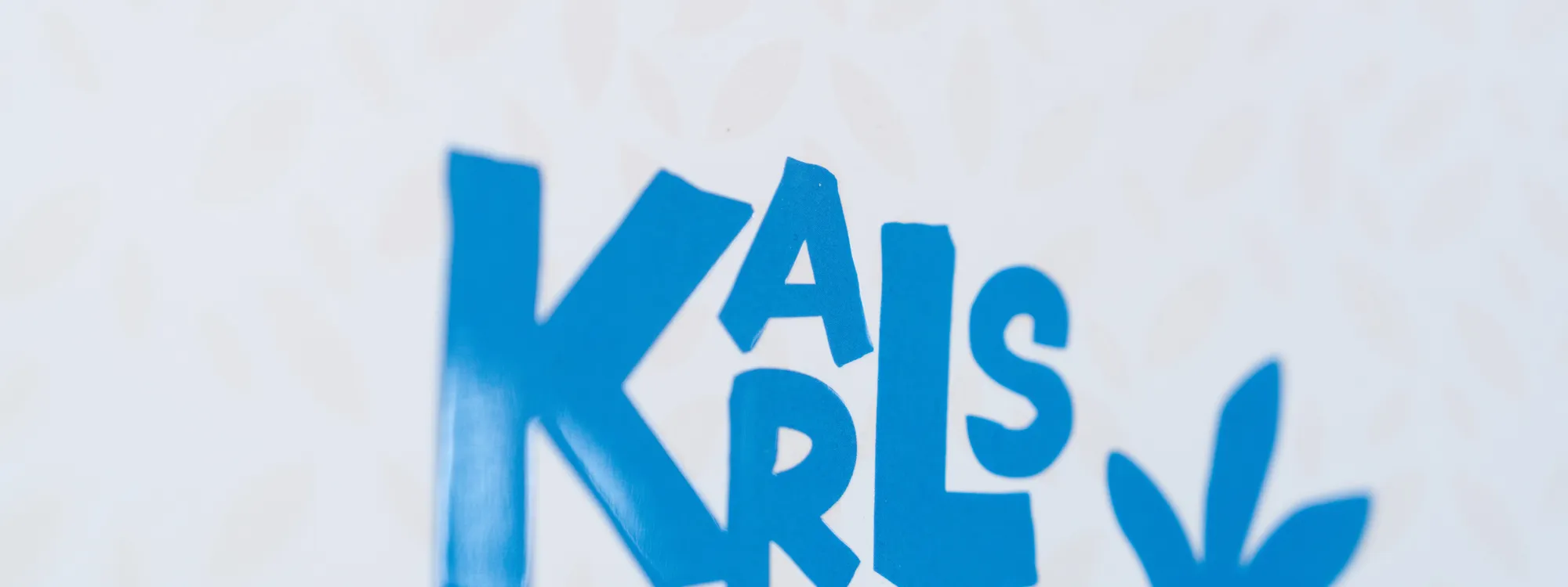 Ein blauer Schriftzug „Karlsruhe“ glänzt partiell lackiert auf einer hellen Karte mit zartem Blattmuster.