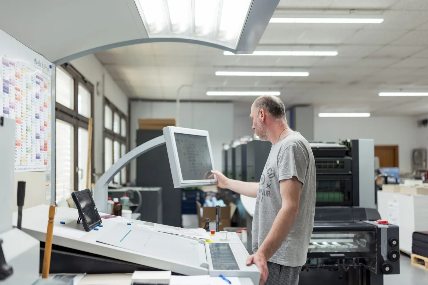 Ein Drucker stellt am Leitstand die Farbzonen der Offsetmaschine ein.