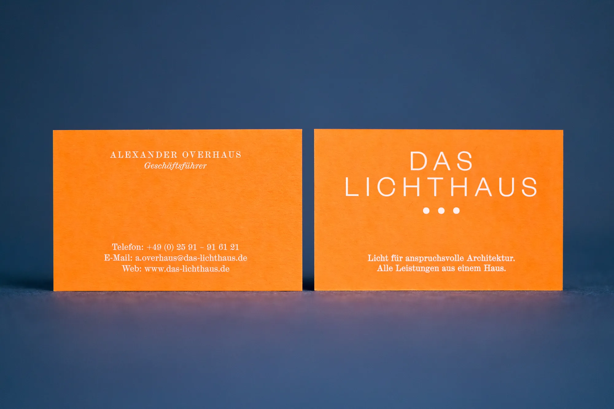 Zwei orange Visitenkarten mit weißem Digitalweißdruck „Das Lichthaus“ auf blauem Grund.