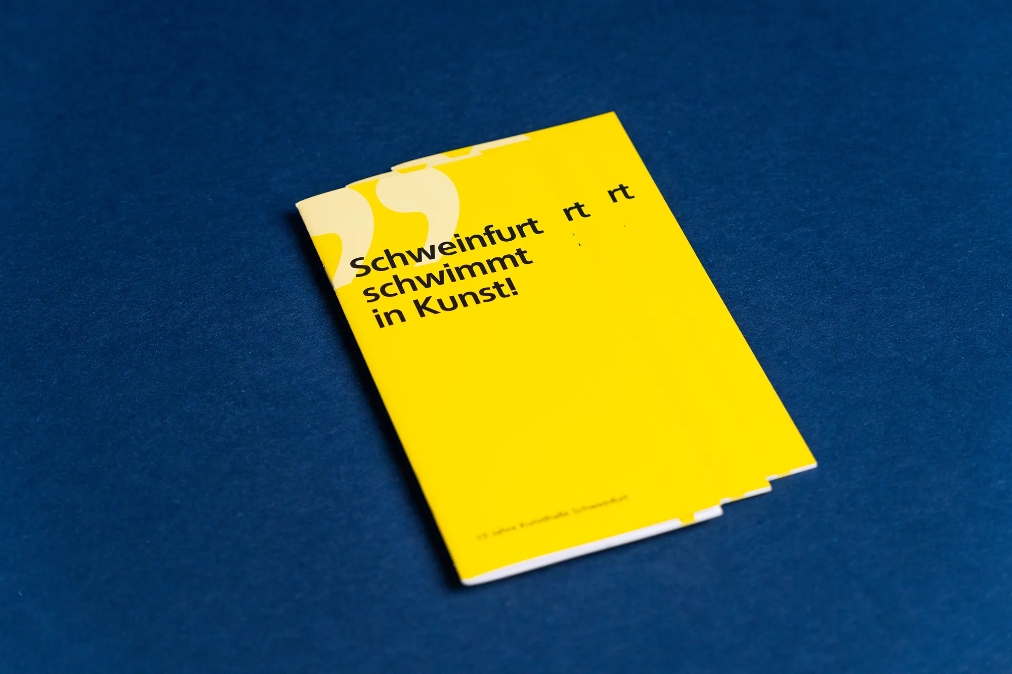 Leuchtend gelbes schmales Programmheft „Schweinfurt schwimmt in Kunst!“ auf blauem Grund.