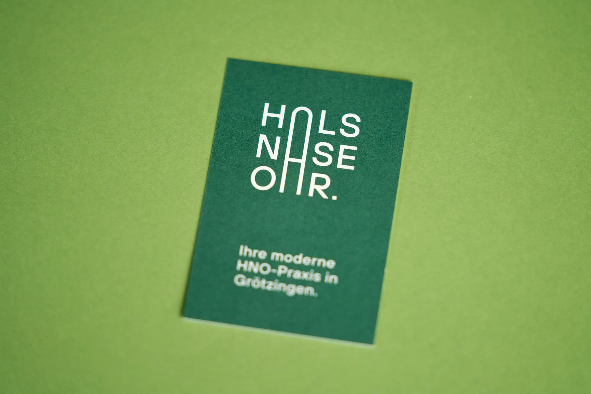 Grüne Visitenkarte einer HNO-Praxis mit weißer Schrift auf grünem Grund.