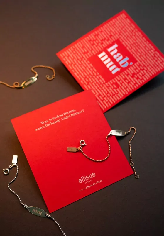 Rote quadratische Schmuck-Trägerkarten mit eingehängten Ohrringen auf dunklem Grund.