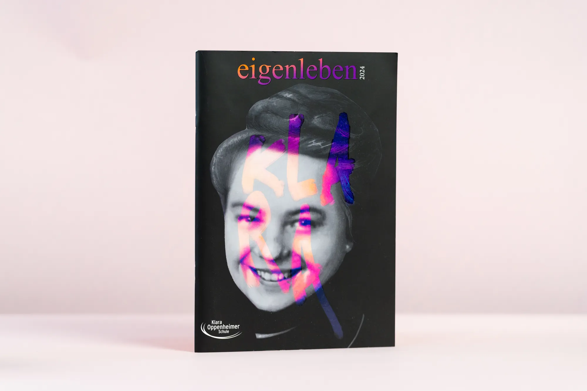 Schülerzeitung „eigenleben“ mit Schwarz-Weiß-Porträt und Neonfarben vor hellem Grund.